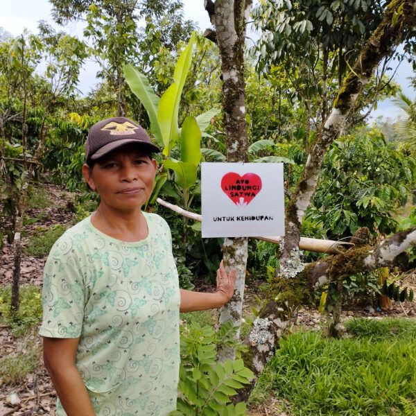 a woman stands with a sign in Indonesian